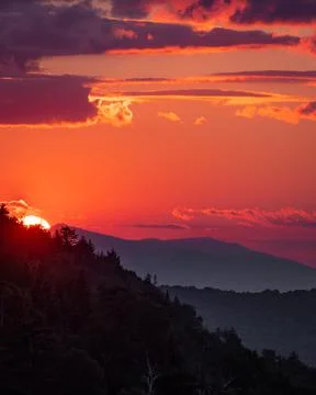 The sky lights up red as the sun sets in the mountains Stock Photos