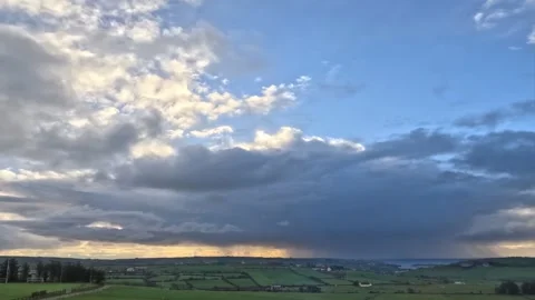 The sky is mostly cloudy. The ground is a patchwork of green fields Stock Footage 285254820