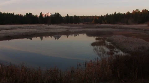 SKY REFLECTED IN MEADOW POND AND MOUNTAIN IN BACKGROUND Stock Footage 52553201