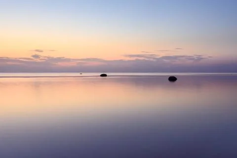The sky is reflected in the sea at sunset on a long exposure. Stock Photos