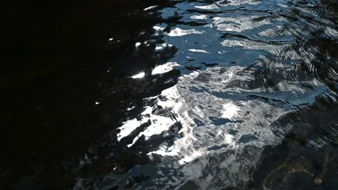 The sky reflecting on waves from a mountain stream (slow motion) Video stock 219649547