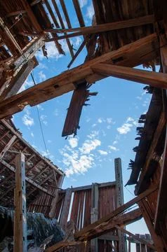 The sky seen through the collapsed roof of an old barn. Stock Photos