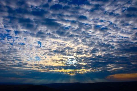 A sky with the sun shining through clouds. Stratus clouds at sunset. Stock Photos
