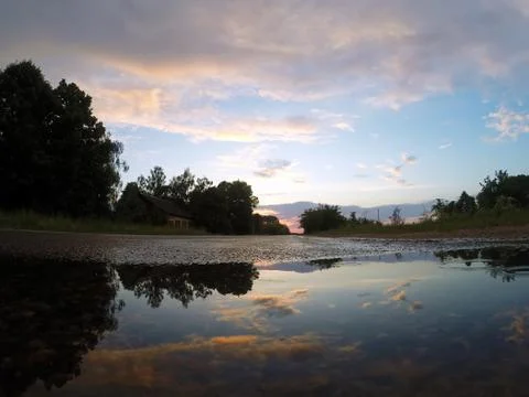 The sky at sunset is reflected in a puddle, Stock Photos