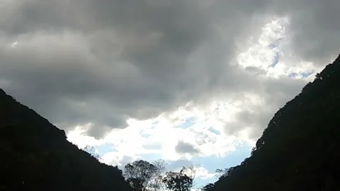 Sky time lapse between mountains storm clouds to sun Video stock 134992712