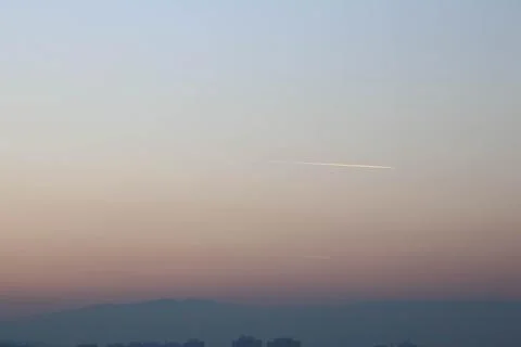 Sky view during sunset with mountains and trace of airplane. Stock Photos