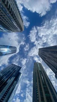 Sky view from the ground level among tall buildings with clouds in the back.. Stock Photos