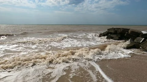 The sky was clear and the waters of the sea beat on the rocks Stock Footage 168579044