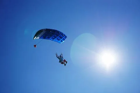 Skydiver with a blue parachute close up under sunshine Stock Photos