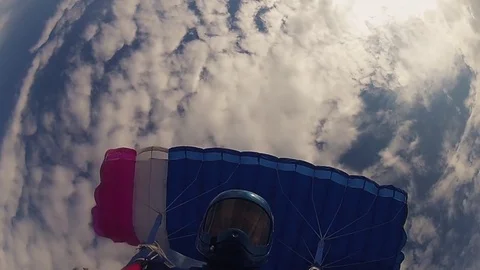 Skydiver in helmet parachuting in cloudy sky. Sunny day. Extreme sport. Speed. Stockbeeldmateriaal 79512928