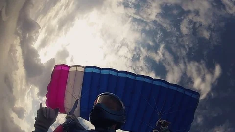 Skydiver in helmet parachuting in cloudy sky. Height. Prepare to landing. Speed. Video stock 79513012