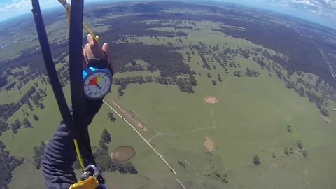 A skydiver looks at her altimeter while parachuting. Stockbeeldmateriaal 71250406