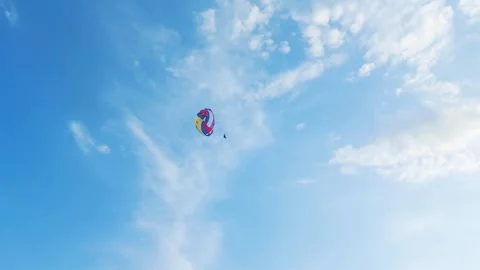 Skydiver with multi-colored parachute against blue sky, parachuting sport. Copy Stockbeeldmateriaal 303621107