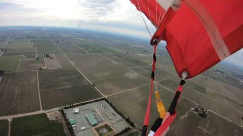 Skydiver Navigating His Red Parachute Toward the Ground Below Stock Footage 208739103
