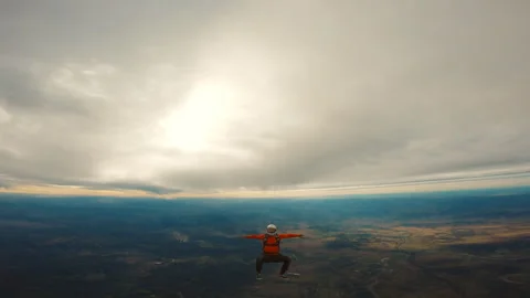 Skydiver in orange jacket falling down Stock Footage 264503056