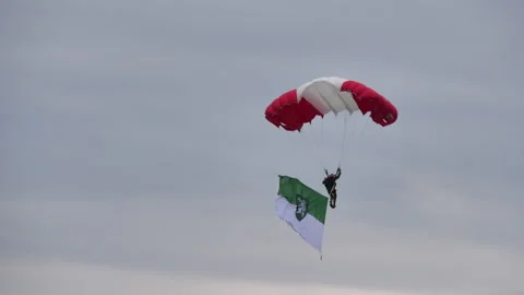Skydiver with a parachute in the red and white colors of the Austrian flag lands 動画素材 158180996