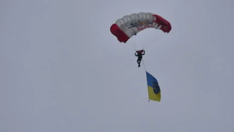 Skydiver with a parachute in the red and white colors of the Austrian flag lands 動画素材 158198311