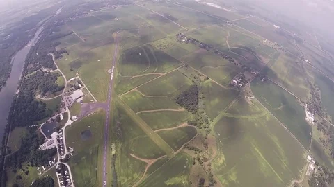 Skydiver parachuting above green fields. River. Extreme activity. Adrenaline Stockbeeldmateriaal 69965167