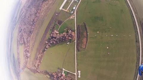 Skydiver parachuting in cloudy sky above green field. Extreme sport. Landscape. Видео 96440691