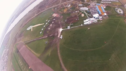 Skydiver parachuting in cloudy sky above green field, city. Landing. Landscape. Видео 96443569