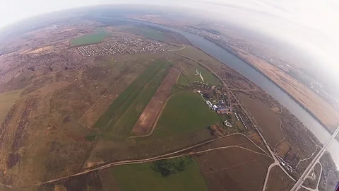 Skydiver parachuting in cloudy sky above green field, river. Height. Scenery. Stock Footage 96446315