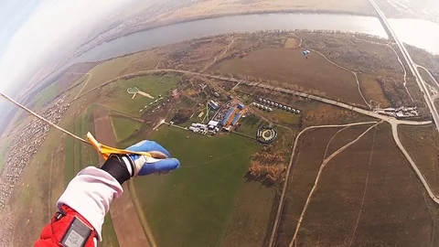 Skydiver parachuting in cloudy sky above green field. Height. Landscape. Sun Stock Footage 96446603