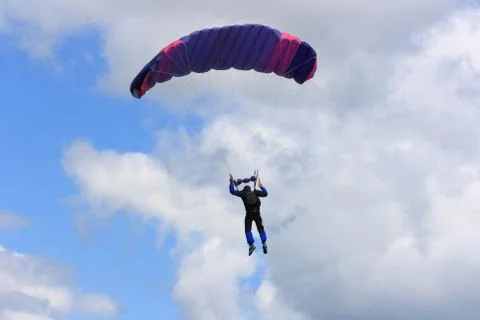 Skydiver parachuting down to the earth. Stock Photos