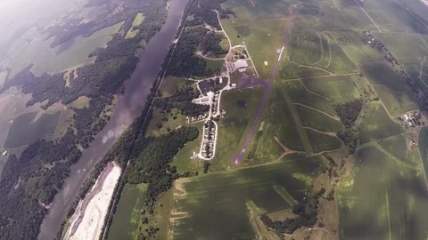 Skydiver parachuting over green fields, river. Extreme activity. Adrenaline Stockbeeldmateriaal 69965847