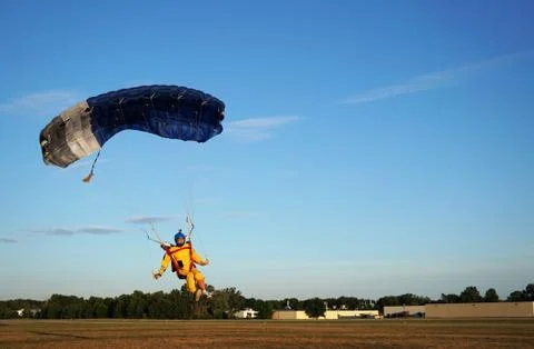 Skydiver under a small blue canopy of a parachute is landing on airfield, spe Foto stock
