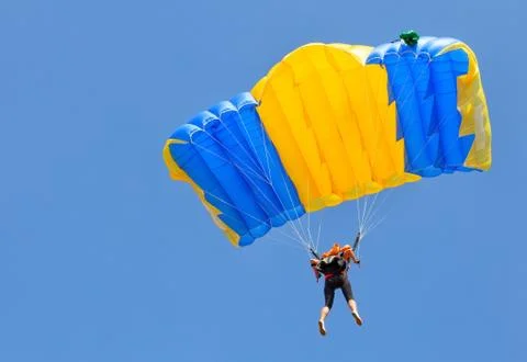 Skydiver under yellow and blue parachute dome Stock Photos