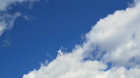 Skydiver on a white parachute glides through the air between beautiful white Video stock 220288139