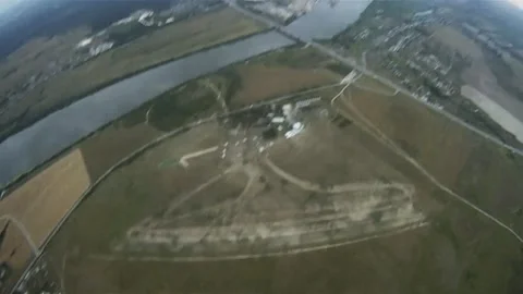 Skydivers parachuting in grey sky above green flatland. Extreme sport. Stormy Stock Footage 152064065
