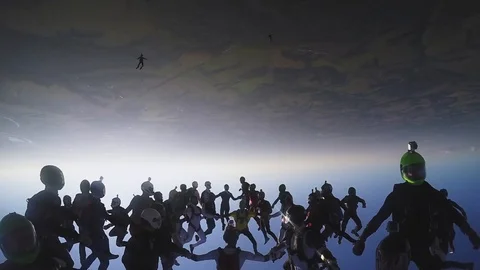 Skydivers team in uniform falling in sky. Create formation. Parachuting. Sun. Stockbeeldmateriaal 95098528