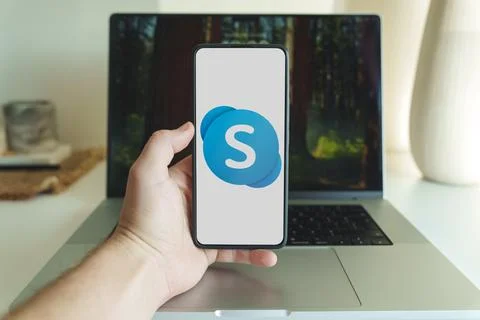 Skype application logo on smartphone screen in front of laptop Stock Photos