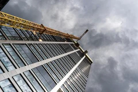 Skyscraper and the crane with dramatic sky in the background Stock Photos
