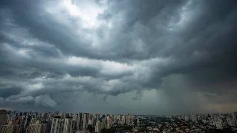 The skyscraper on the background of a rainy cloud. Stock Photos