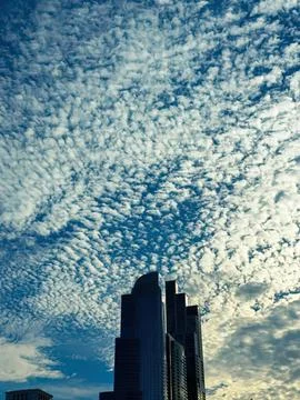 Skyscraper building under cloudy sky in city at sunset Stock Photos