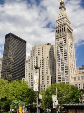 A skyscraper with a clock sits tall against the daytime sky Stock Photos