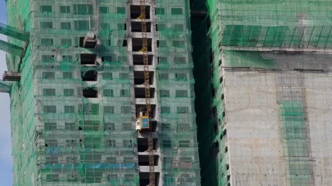 Skyscraper Construction Site with Green Safety Netting and External Elevator Stock Footage 330698193