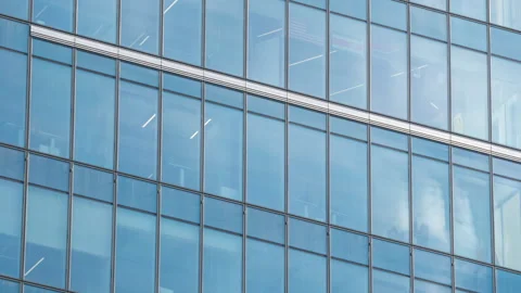 Skyscraper glass facade reflecting moving clouds, blue sky mirrored in windows Stock Footage 335031009