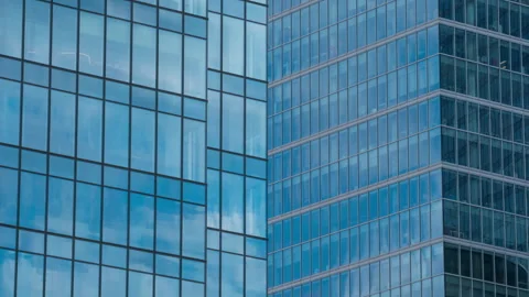 Skyscraper glass facade reflecting moving clouds, blue sky mirrored in windows Stock Footage 335031032