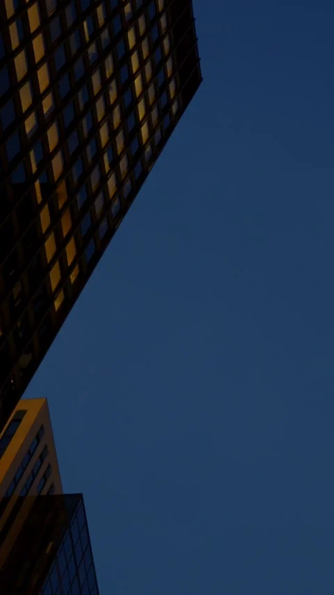 Skyscraper illuminated during twilight. Dusk sky enhances towering glass Stock Footage 344732911