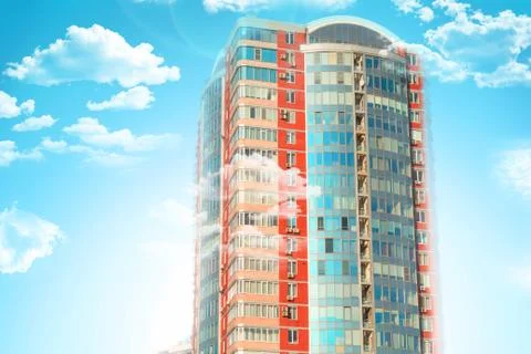 Skyscraper or flat block building on clouds and blue sky background. Closeup  写真素材