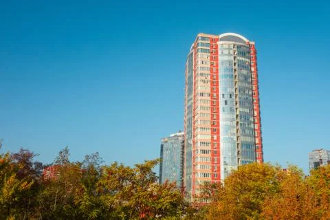 Skyscraper or flat block building on clear blue sky and autumn trees backgrou Photos