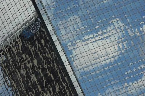 Skyscraper reflecting sky and clouds in glass facade, abstract urban scene Stock Photos