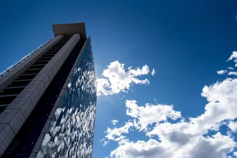Skyscraper with reflections of cloudy sky on its glass facade Stock Photos