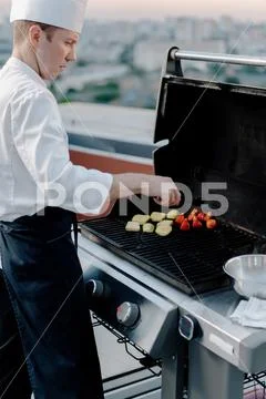 Skyscraper Rooftop: professional chef prepares a barbecue at a party or ...