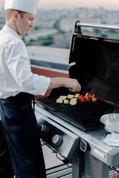 Skyscraper Rooftop: professional chef prepares a barbecue at a party or outdo Fotos Stock