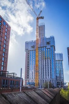 Skyscraper under construction with crane against a bright blue sky. Manches.. Stock Photos
