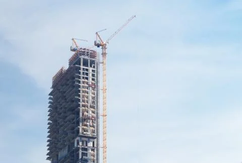 Skyscraper under construction with crane on blue sky background Stock Photos